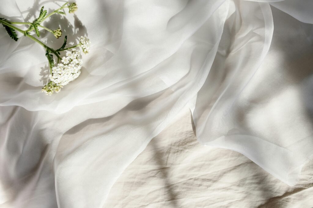 Soft white fabric adorned with delicate flowers, bathed in gentle sunlight.